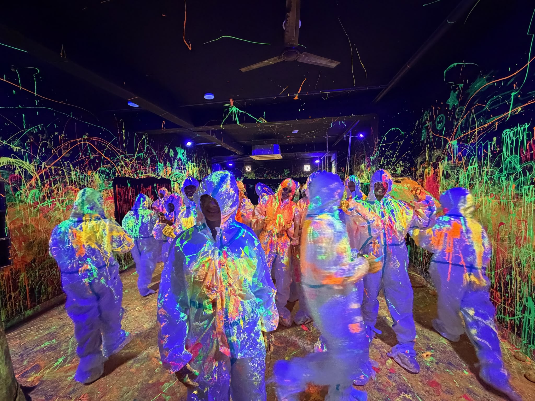 Guests throwing glow-in-the-dark paint in the UV neon splatter room